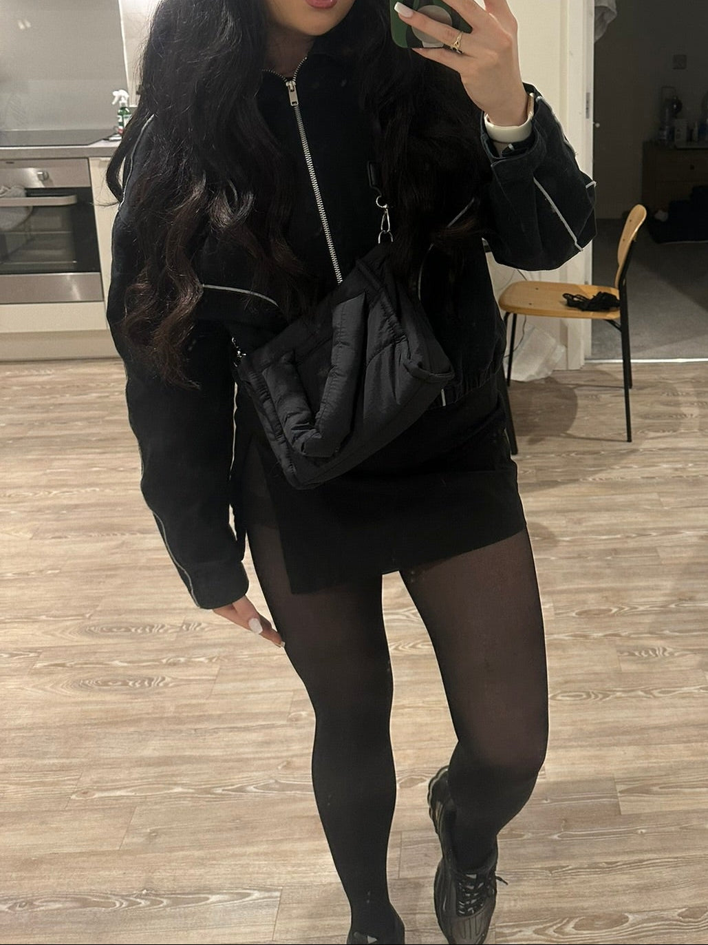 Person taking a mirror selfie in a modern living room with a nylon puffer handbag 